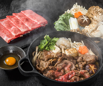 Eine Pfanne mit dampfendem hauchdünn geschnittenem Rindfleisch, Pilzen und Koriander. Im Hintergrund sind weitere frische Zutaten. 