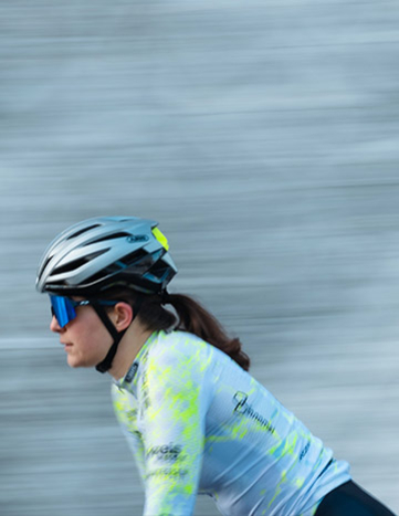 Radfahrerin des Cycling Team Ost in Bewegung mit verschwommenem Hintergrund, der die Geschwindigkeit anzeigt.