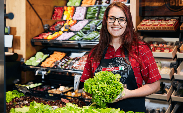 Eine Mitarbeiterin des EUROSPAR Markts präsentiert frisches Gemüse