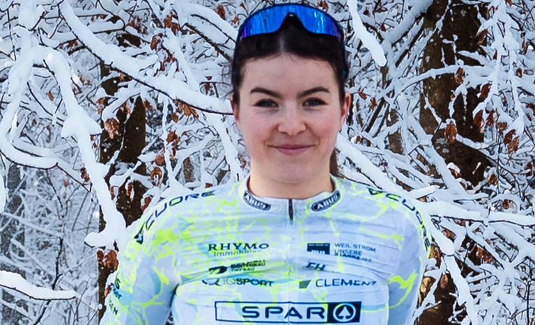Radfahrerin des Cycling Team Ost steht in einer verschneiten Waldlandschaft.