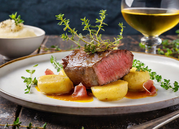 Ein Steak mit Kartoffeln und Kräutern auf einem Teller.