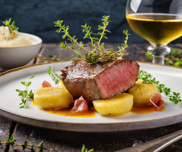 Ein Steak mit Kartoffeln und Kräutern auf einem Teller.