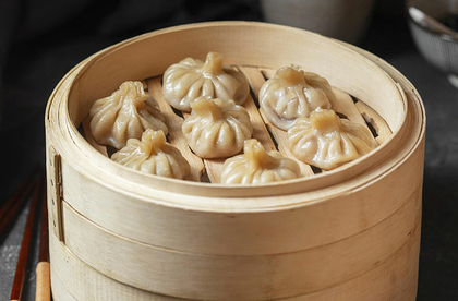Chinesische Knödel in einem Holzbehälter mit Essstäbchen.