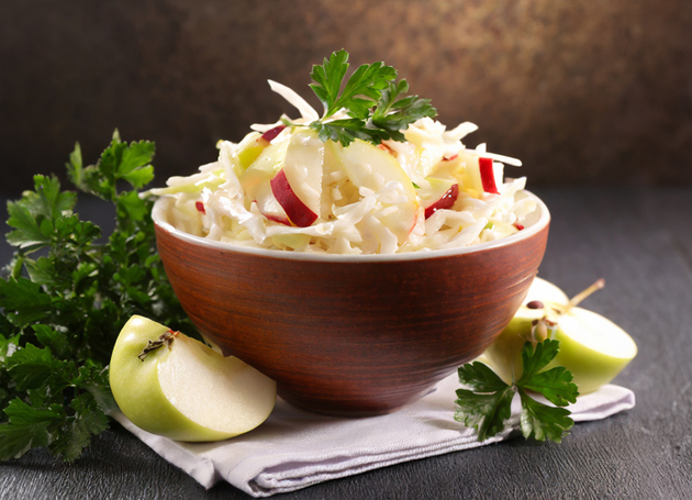 Krautsalat in einer Schüssel mit Äpfeln und Petersilie.