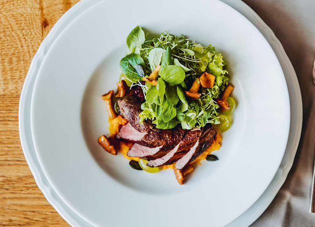 Herbstlicher Blattsalat mit Eierschwämmen und Wildschweinfilet auf Kürbisbett