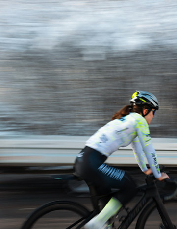 Radfahrerin des Cycling Team Ost fährt durch eine verschneite Waldlandschaft.