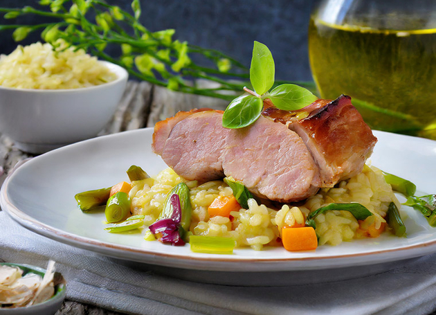 Ein Teller Reis mit Schweinefleisch und Gemüse darauf.