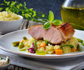 Ein Teller Reis mit Schweinefleisch und Gemüse darauf.