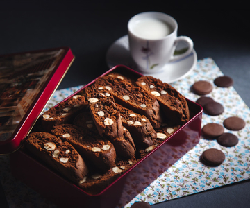 Schokoladecantuccini in einer roten Dose mit einer Tasse Kaffee.