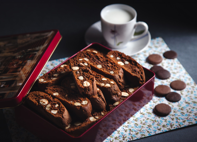 Schokoladecantuccini in einer roten Dose mit einer Tasse Kaffee.