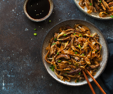 Zwei Schüsseln asiatische Nudeln mit Fleisch.