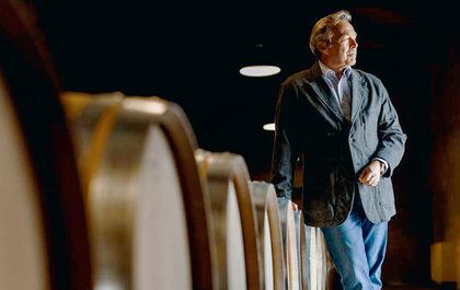 Ein charmantes Bild zeigt einen Weinfass, umgeben von einem Menschen, der die Hand auf das Holz legt und die reiche Geschichte des Weins zu spüren scheint.