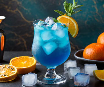 Ein blauer Cocktail mit Orangenscheiben und Eis.