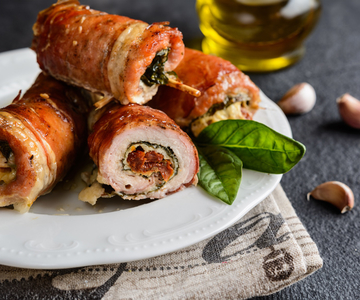 Gefüllte Schweinerouladen mit Spinat und Knoblauch auf einem Teller.