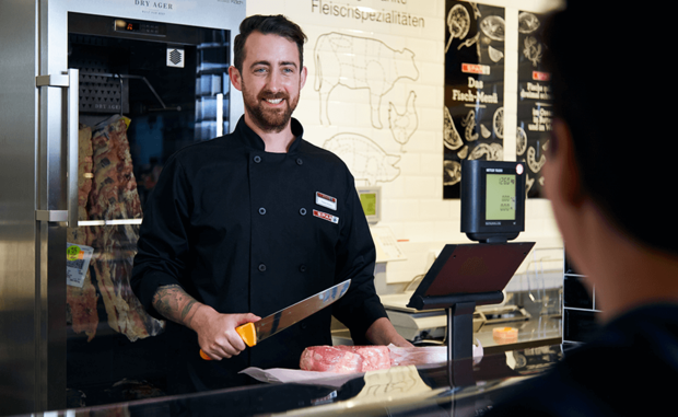 Der Metzger in der bedienten EUROSPAR Metzgerei portioniert Fleisch